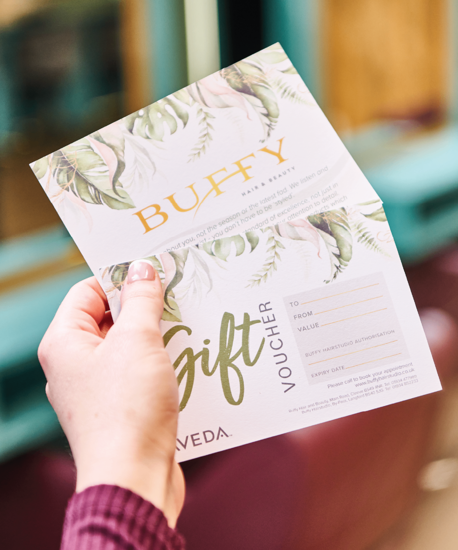 A hand holding the Buffy Hair & Beauty gift voucher