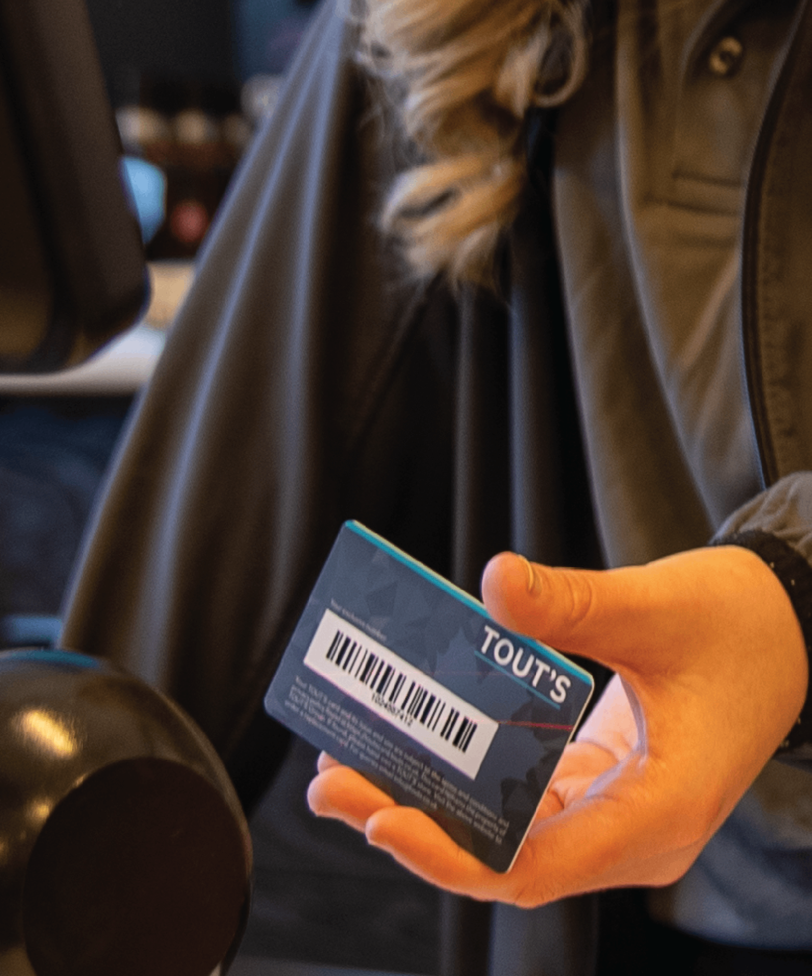 A customer holding a TOUT'S loyalty card at the forecourt
